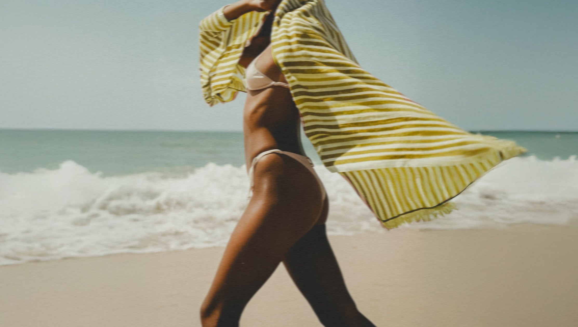 Person on a beach with a yellow striped towel